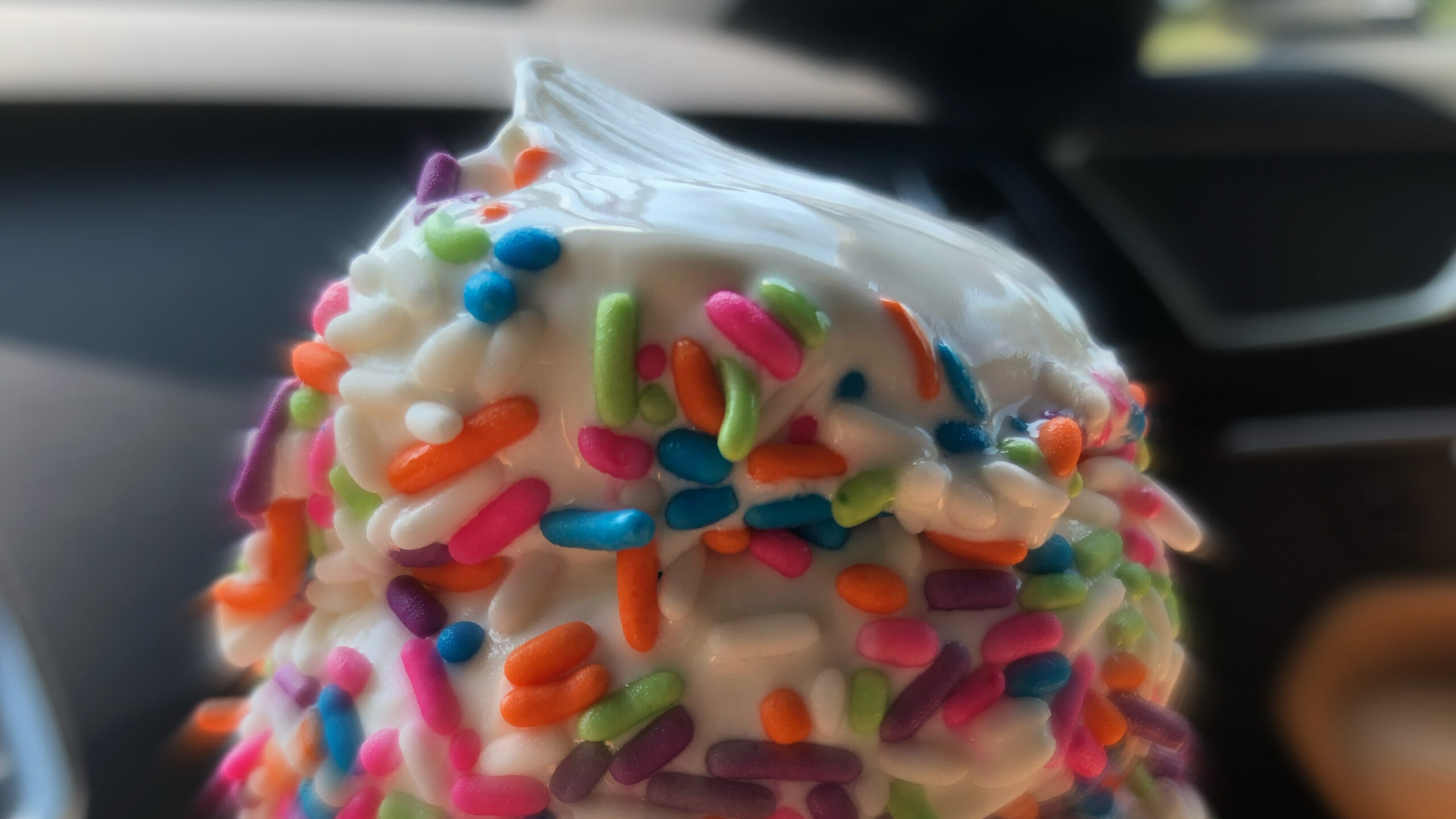 The top of a vanilla ice cream cone with rainbow sprinkles.