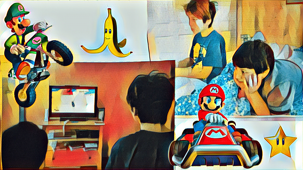 Will playing Mario Kart, Mikey watching with his head in his hands, smiling.