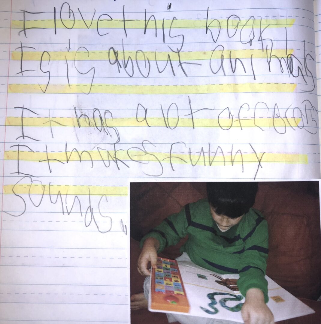 Mickey's journal entry from February 1, 2014. Photo of Mikey reading an Eric Carle animal book with photos animals and buttons with their corresponding sounds. "I love this book. It is about animals. It has a lot of colors. It makes funny sounds.