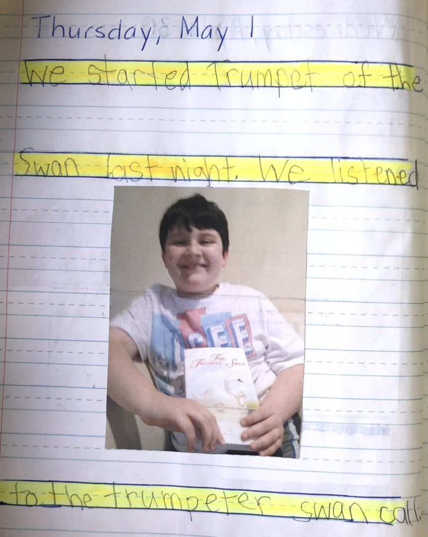 journal from May 1, 2014. "We started trumpet of the swan last night. We listened to the trumpeter swan call." photo of mikey proudly smiling with his book.