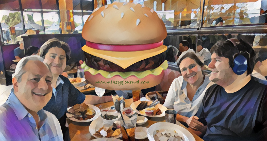 Our family around the table at Cheesecake Factory with the other diners obscured with a giant cheeseburger sticker.