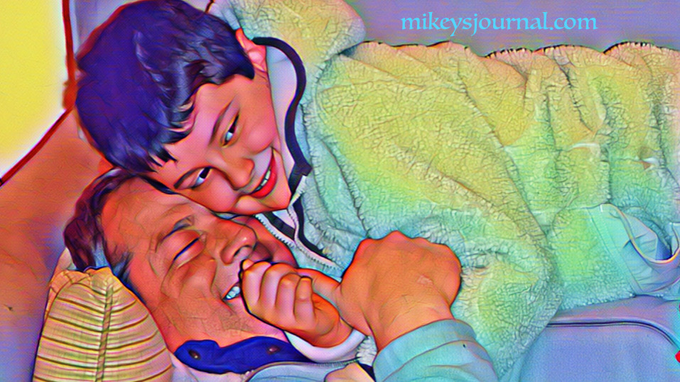 Mikey piled on top of Dave on the couch. They're both cracking up.