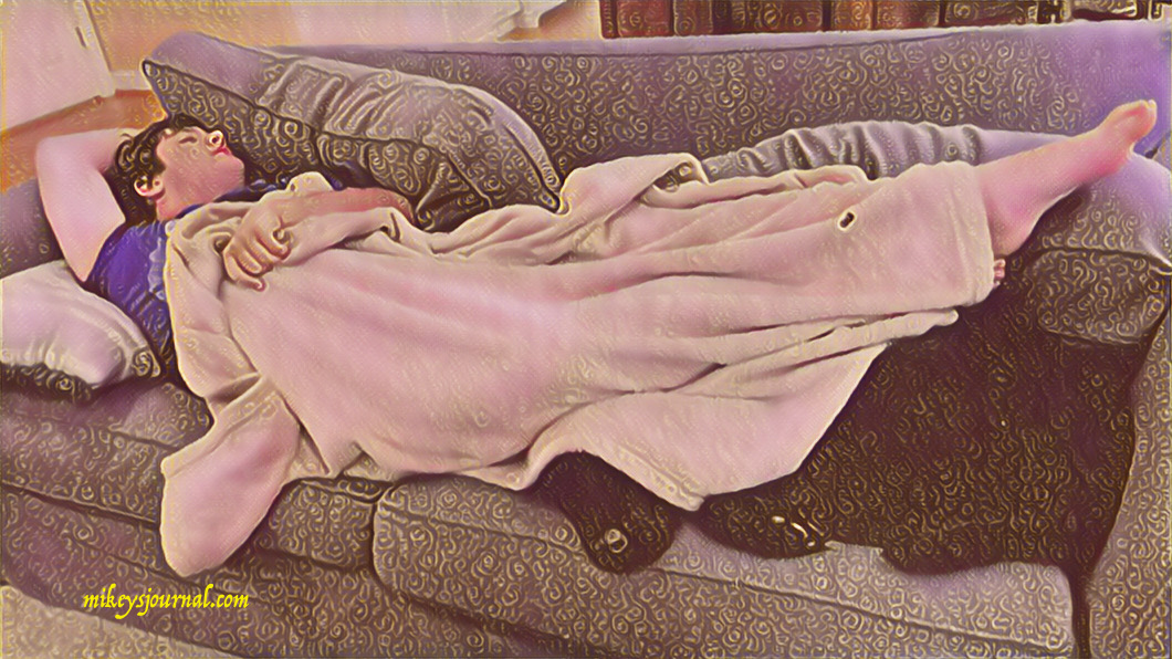Mikey napping on the couch with a blanket, legs covering our black lab Sonny.