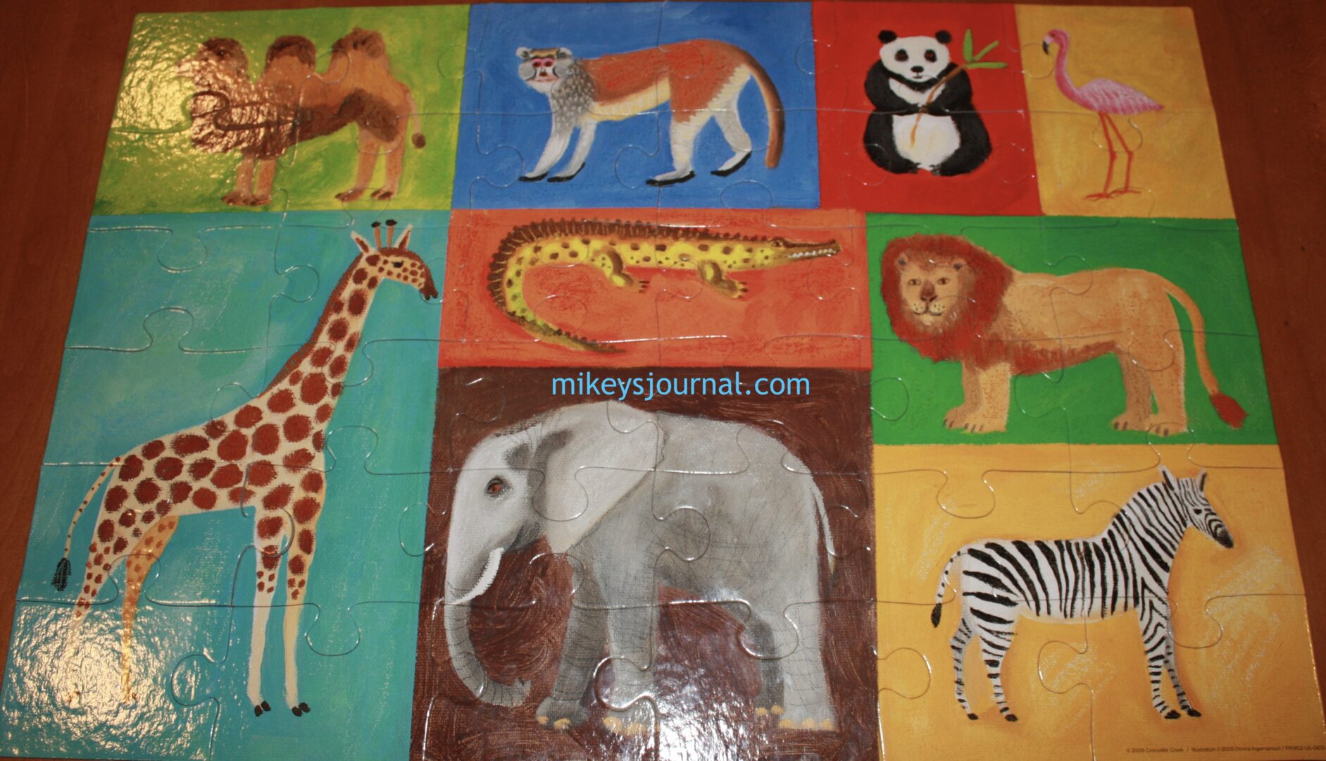 puzzle with colorful blocks, each one containing a painted image of an animal (camel, monkey, panda,flamingo, giraffe, lion, elephant and zebra).