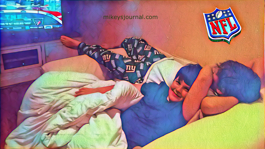 stylized photo of Mikey and Will lounging on an oversized chair in front of the football game on TV