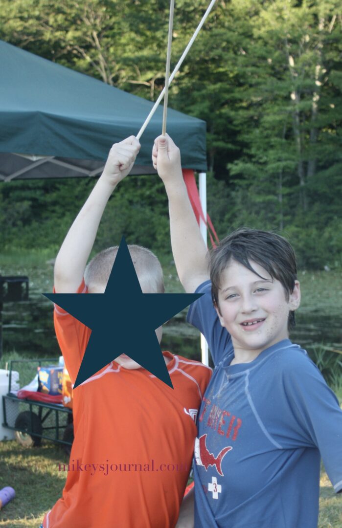 Will and his friend posing with their s’mores sticks above their heads at the park.