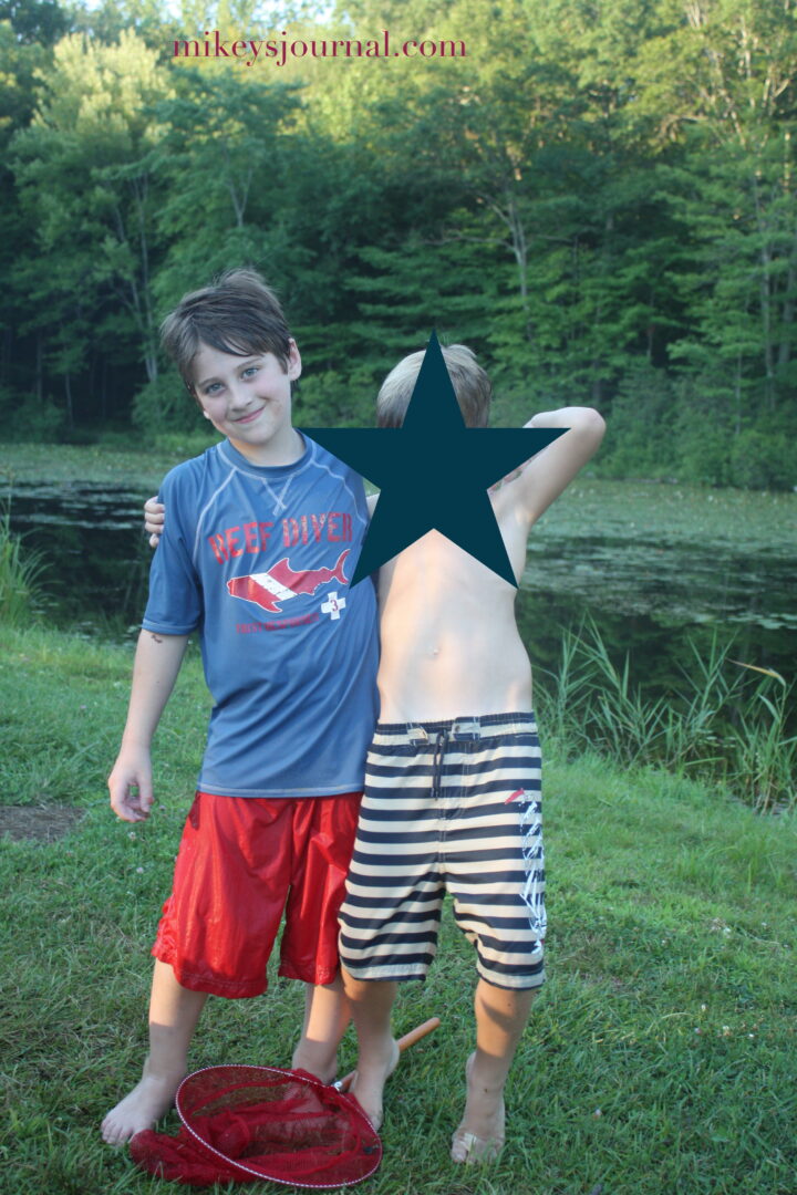 Will posing with a friend at the park with one of their frog catching nets on the grass between them.