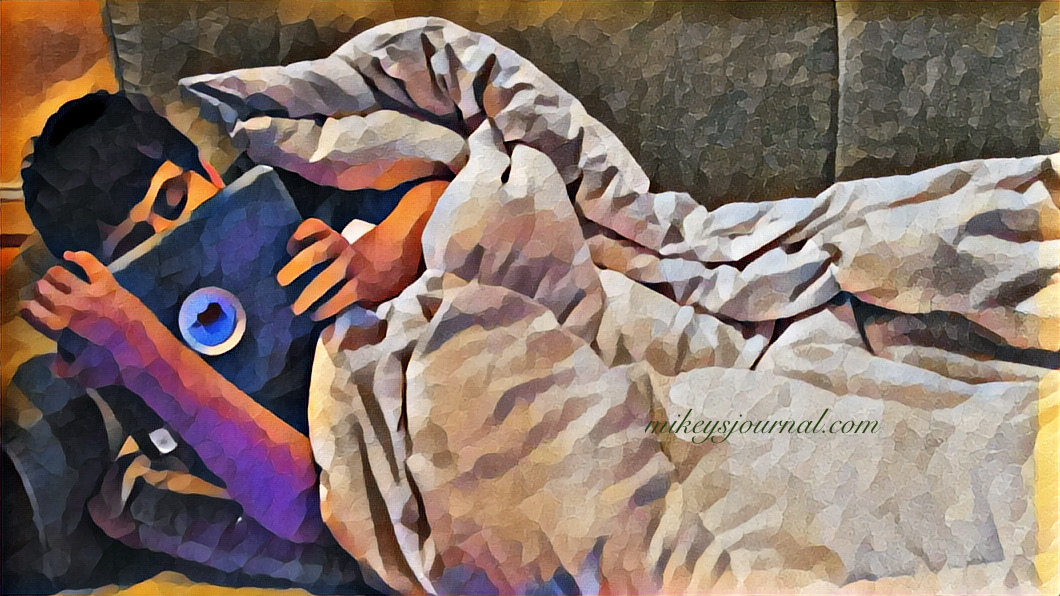 stylized photo of mikey cuddled under his white blanket watching something on his ipad.