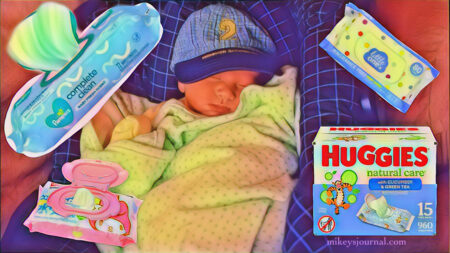 Will as a baby in his carrier, wrapped in a blanket and wearing a little had with the number 2 on it, surrounded by baby wipes.