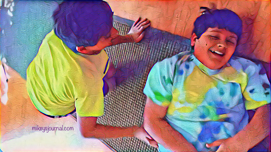 8CEC4C05-F48C-4DC0-BCF7-74ADB6CA2C94 stylized photo of Mikey laughing on the floor while Will tickles him.