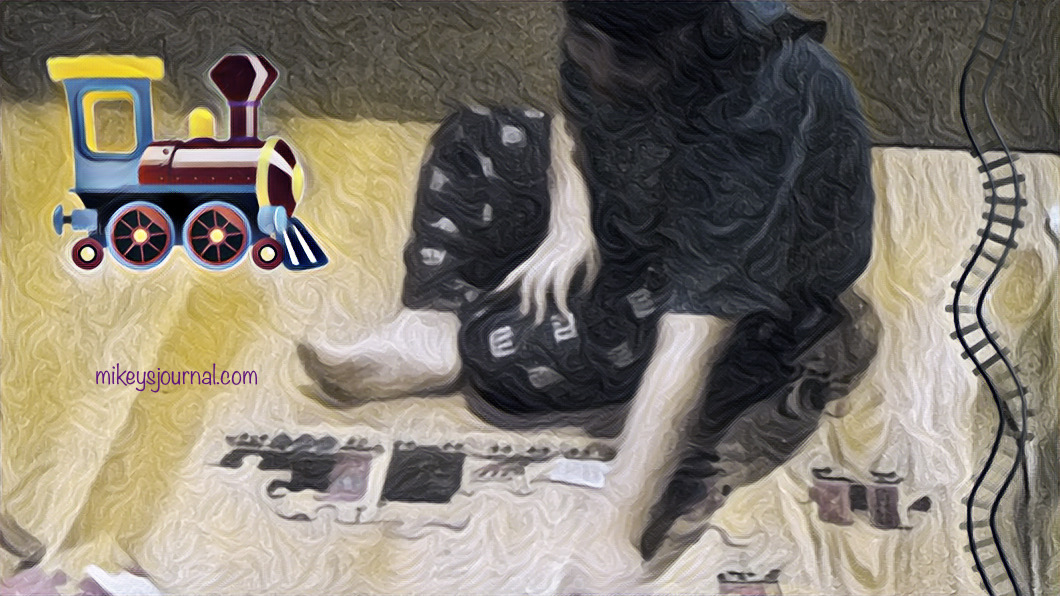 stylized photo of mikey working on the train puzzle on the floor with a train sticker and a sticker of train tracks added for fun.