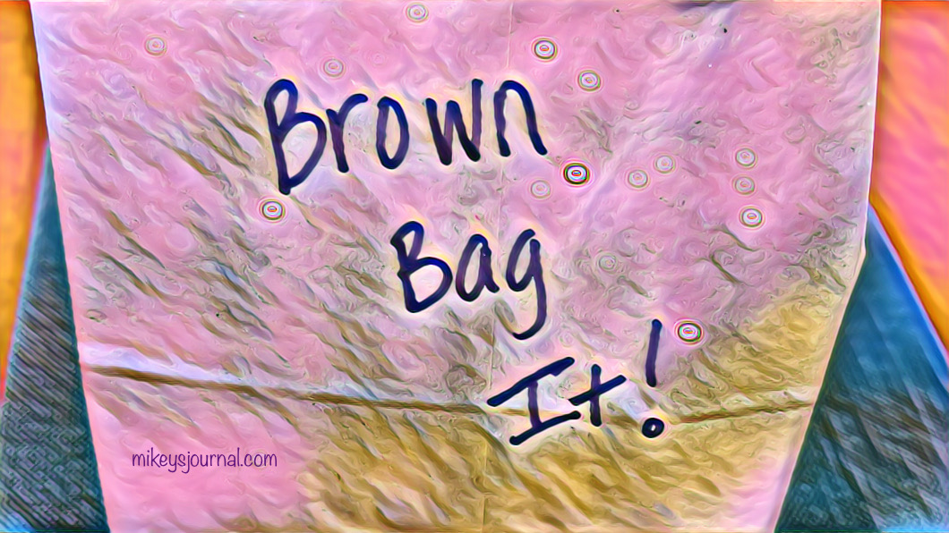 stylized photo of a brown bag labeled Brown Bag It! sitting on our wood kitchen table on a green placemat.